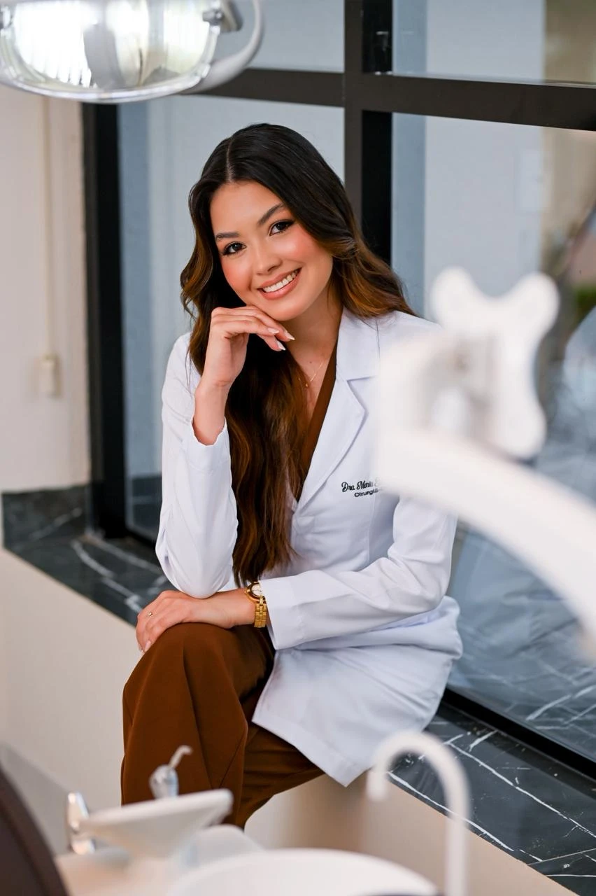Dra. Maria Eduarda Goulart sorrindo em seu ambiente de atendimento